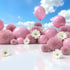 Rosa Kugeln, flauschige Pompons und weiße Gänseblümchen auf reflektierendem Boden unter blauem Himmel mit Wolken.
