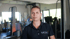 Frau in schwarzem Poloshirt mit "MOVE" Logo steht in einem Fitnessstudio.