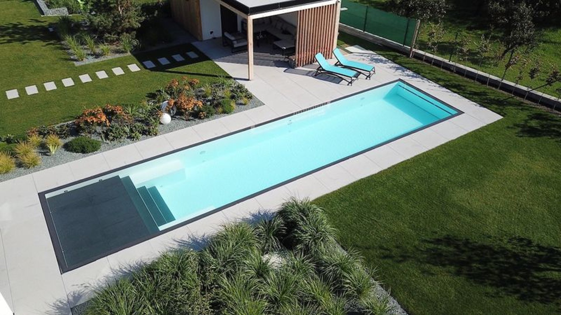 Rechteckiger Pool mit klarem Wasser, umlaufendem Pflaster und moderner Poolhütte in einem Garten im Main-Taunus-Kreis