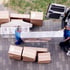 Zwei Umzugshelfer in blauen Shirts tragen ein großes, verpacktes Möbelstück aus einem Transporter, umgeben von Kartons.