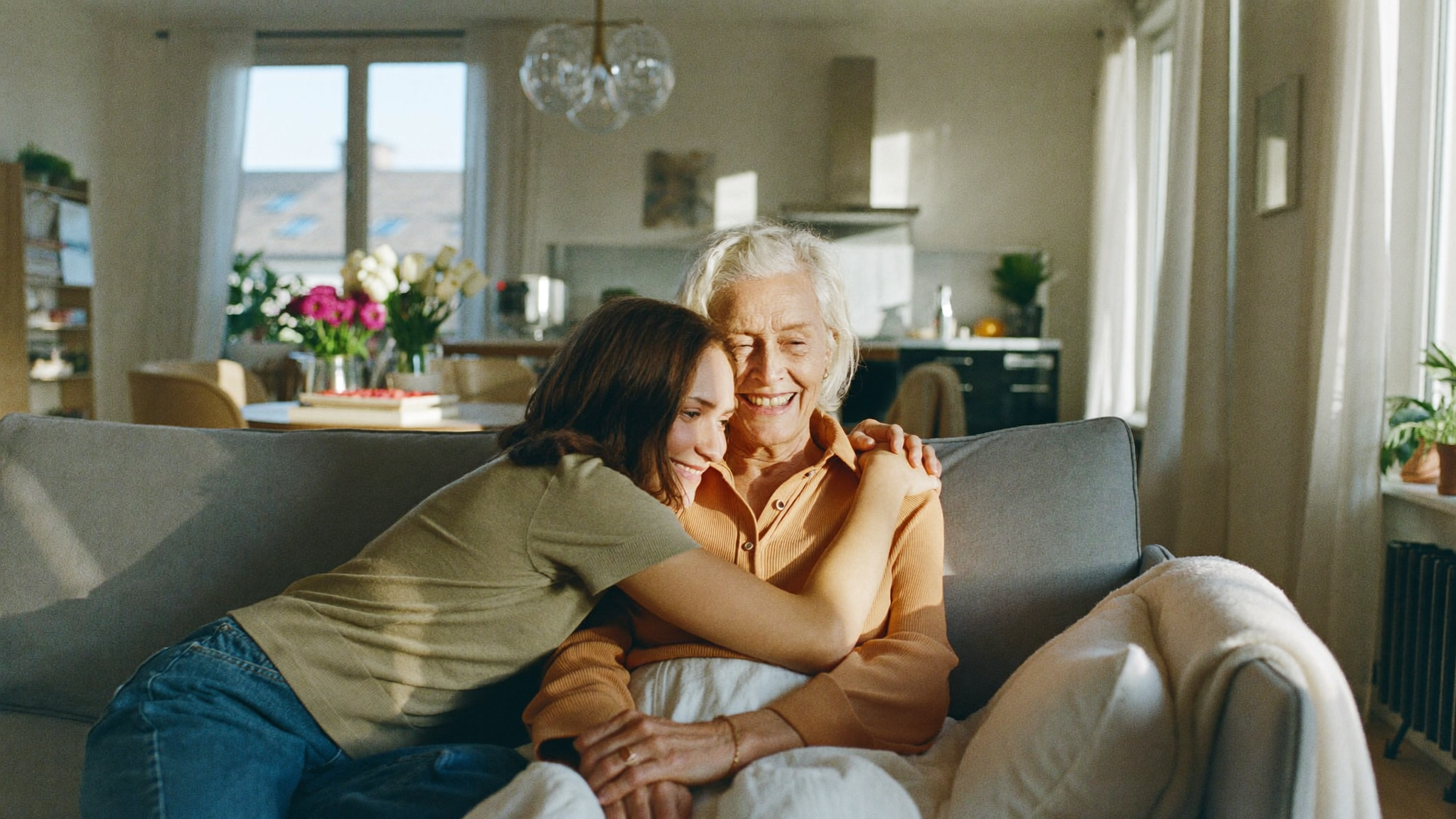 Tochter umarmt ihre pflegebedürftige Mutter zuhause auf dem Sofa