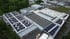 Luftaufnahme einer Fabrikanlage mit mehreren Gebäuden und Solarmodulen auf den Dächern.