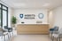 Empfangsbereich mit Holztheke, zwei grauen Sesseln, Pflanze und „ARBEITS-MEDIZIN“ Logo an der Wand.