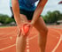 Person in athletic wear clutching a knee, indicating pain.
