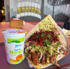 Döner Kebab mit Fleisch, Salat und Soße auf einem Teller neben einem Becher Ayran Mango.