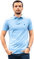 Marcel Hüsig in einem hellblauen Poloshirt mit einem Logo und dunklen Jeans, die Hände in den Taschen.