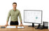 Ein lächelnder Mann im Hemd steht an einem Schreibtisch neben einem Monitor, der ein ERP-System Dashboard zeigt.