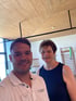 Ein lächelnder Physiotherapeut von LANDphysio und eine Patientin in einem hellen Trainingsraum mit Sprossenwand.