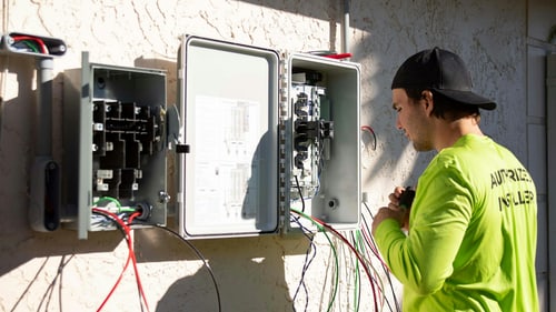 A security technician mounting a device on an interior wall