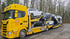 Gelber ADAC Scania Autotransporter-LKW mit mehreren beladenen Autos auf einer Straße.