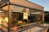 Terrasse mit transparenten Seitenrollos, Liegestuhl, Esstisch und Poolbereich bei Sonnenuntergang.