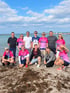 Gruppe am Strand, mehrere Personen tragen pinke Diakonie-Laufshirts.