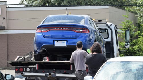 Flatbed tow truck loading a car, illustrating towing cost in Port Charlotte