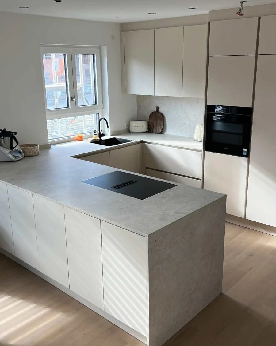 Grifflose Küche in Creme-Magnolie mit Halbinsel und Arbeitsplatte aus Dekton Sabbia