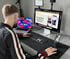 Ein Mann sitzt an einem Schreibtisch mit zwei Monitoren, Laptop, Tastatur und Maus.