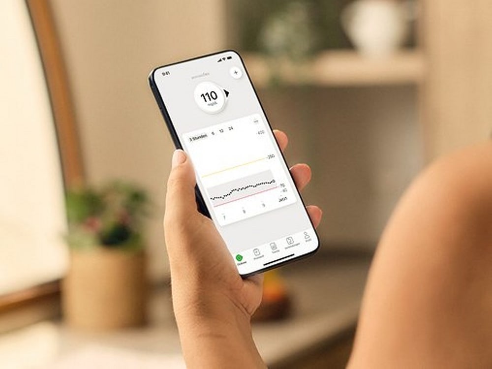 Hand hält Smartphone mit geöffneter Dexcom Flex App