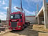 Roter Scania-LKW mit Kran auf einer Baustelle entlädt Betonplatten für ein Gebäude.