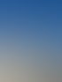 Wanderer stehen auf einem felsigen Berggipfel neben einem goldenen Gipfelkreuz unter blauem Himmel.