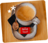 Kaffeetasse mit Löffel, schwarzer Serviette und einem Biscoff Welcome Keks auf einem Tablett.