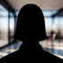 Dunkle Silhouette einer Person mit langen Haaren und verschränkten Armen vor einem hellen Hintergrund.