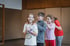 Vier Kinder spielen in einer Turnhalle, das Mädchen vorne lächelt, die anderen berühren ihre Schultern.
