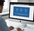 Mann tippt an Tastatur vor einem iMac, der eine Website mit drei Icons und Text anzeigt: "Vertrag kündigen", "Kündigungsfrist", "Anbieterwechsel".
