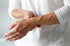 A person holds their painful wrist with their left hand due to osteoarthritis.