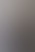 Eine lächelnde Frau mit schulterlangem braunem Haar und schwarzem Pullover sitzt vor einer grauen Wand.