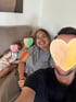 Eine lächelnde Frau mit Brille sitzt mit einem Mann, einem Kind und einem Baby auf einem Sofa.