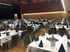 Großer, leerer Festsaal mit vielen Tischen, weiß gedeckt, blauen Servietten und Stühlen.