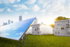 Solarpanel mit mehreren grauen Energiespeichersystemen auf einem grünen Hügel, mit Stadt im Hintergrund.