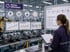 Woman in factory reviews "PROCESS IMPROVEMENT" display with charts, "PROCESS FLOW" diagram, and "KEY IMPROVEMENT FOCUS" list.