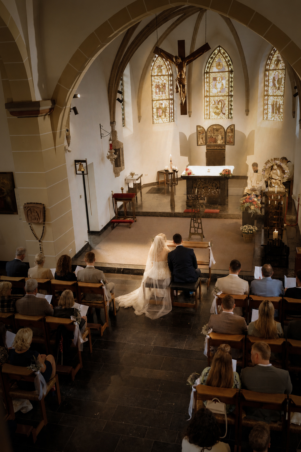 Weiter Blick in die Niederdonker Kapelle in Meerbusch während der Trauung, das Brautpaar sitzt vorn vor dem Altar, die Gäste in den Stuhlreihen.