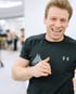 Jacob - Boxtrainer BACKYARD Wien -  Lächelt in die Kamera während im Hintergrund das Boxtraining stattfindet