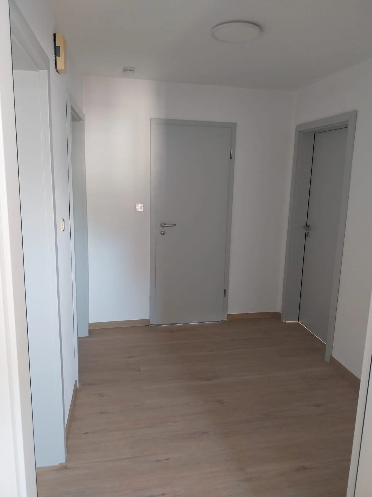 Fertiger Flur mit neuen grauen Innentüren, Zargen und passendem Boden