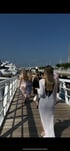 Group of people walking on a wooden boardwalk next to luxury yachts on a sunny day.