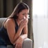 A young woman wipes her nose with a tissue because of allergies.