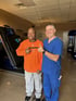 Two men, one in blue scrubs, smiling.


