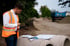 Christian Roßmann analysiert Bauprojektdaten in orangener Sicherheitsweste auf einer Baustelle.
