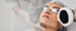 Eine Frau mit Schutzbrille erhält eine Laser-Gesichtsbehandlung durch eine Person in medizinischer Kleidung und Handschuhen.