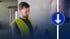 Dominik Walter in Warnweste im Gespräch auf der Baustelle, daneben ein blaues Pfeilschild