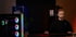 Junger Mann sitzt vor einem PC mit RGB-Beleuchtung und tippt auf einer Tastatur.