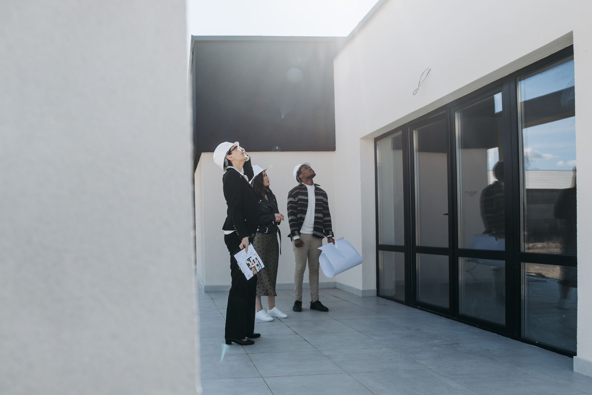 Home buyers and an agent looking up at the roof of a house for sale, part of a roof inspection before buying a house in Joshua