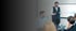 Sieben Geschäftsleute sitzen um einen Konferenztisch mit Laptops und Tassen; "SCHNEIDER" Logo an der Wand.