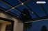Terrassenüberdachung aus Glas und Metall mit LED-Beleuchtung bei Nacht.