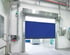 Blaues Schnelllauf-Rolltor aus Kunststoff in einer Industriehalle mit Edelstahlrahmen und angrenzender Fördertechnik.