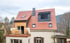Wohnhaus mit neu gedecktem Ziegeldach, Schornstein, Dachgaube und Dachfenstern während einer Sanierung.