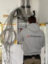 Elektriker in grauem Hoodie installiert Kabel an einem Sicherungskasten.