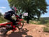 Motocrossfahrer auf orangefarbenem KTM-Motorrad mit Nummer 719, daneben ein Mann mit Schild.