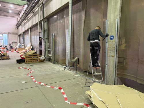 Mitarbeiter auf der Leiter beim Entfernen einer Wandverkleidung